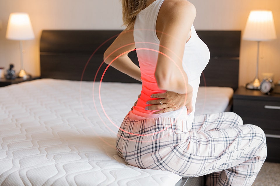 Coir bed vs foam bed: a woman on a bed experiencing back pain.