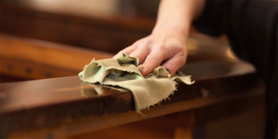 Cleaning a wooden bed with a soft cloth.