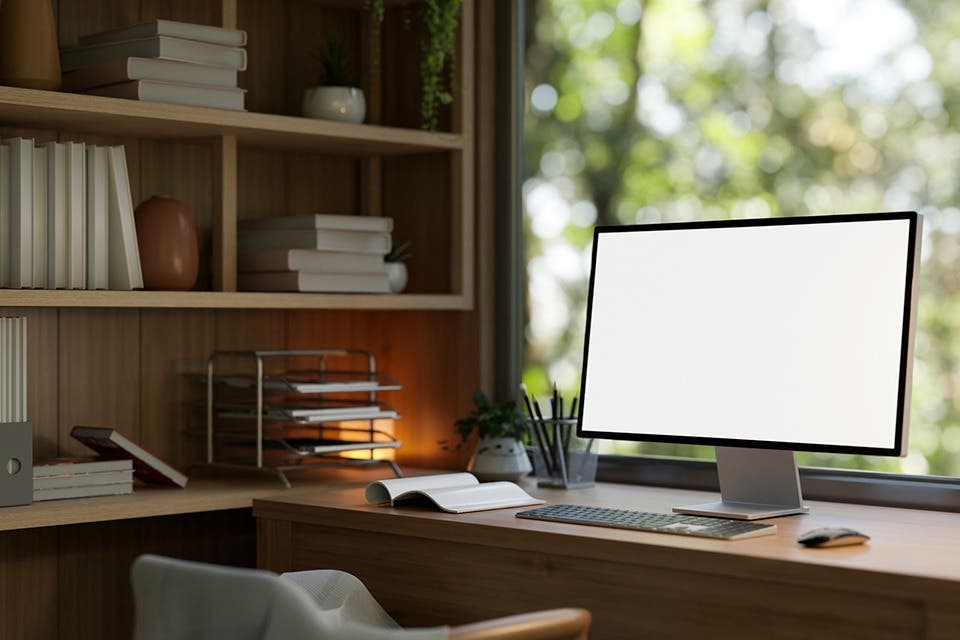  Corner study table with integrated bookshelf beside a window in a compact home office. 