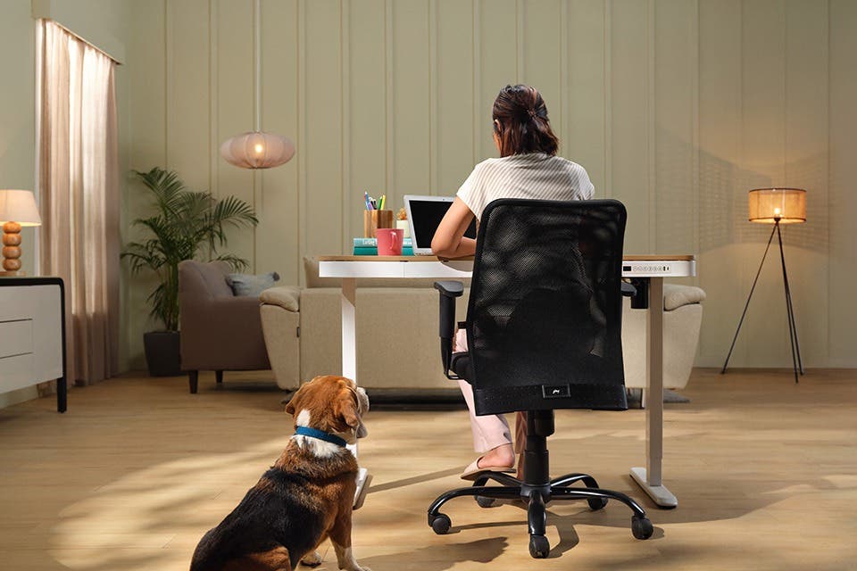 A person at a compact study table and a wheeled chair in a room. 