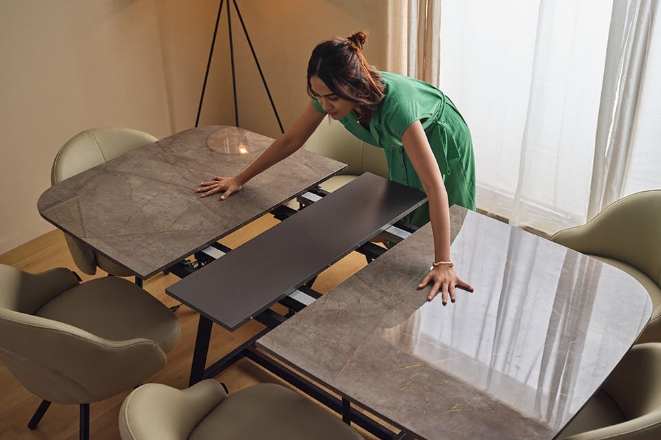 Modern extendable dining table with a stone-effect top and four upholstered chairs in a contemporary open-plan kitchen and dining area.