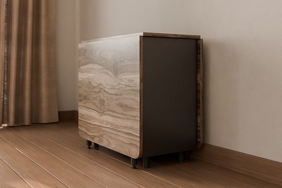The wooden Terrano drop-leaf dining table with fold-down leaves and integrated storage placed against a modern dining room wall.
