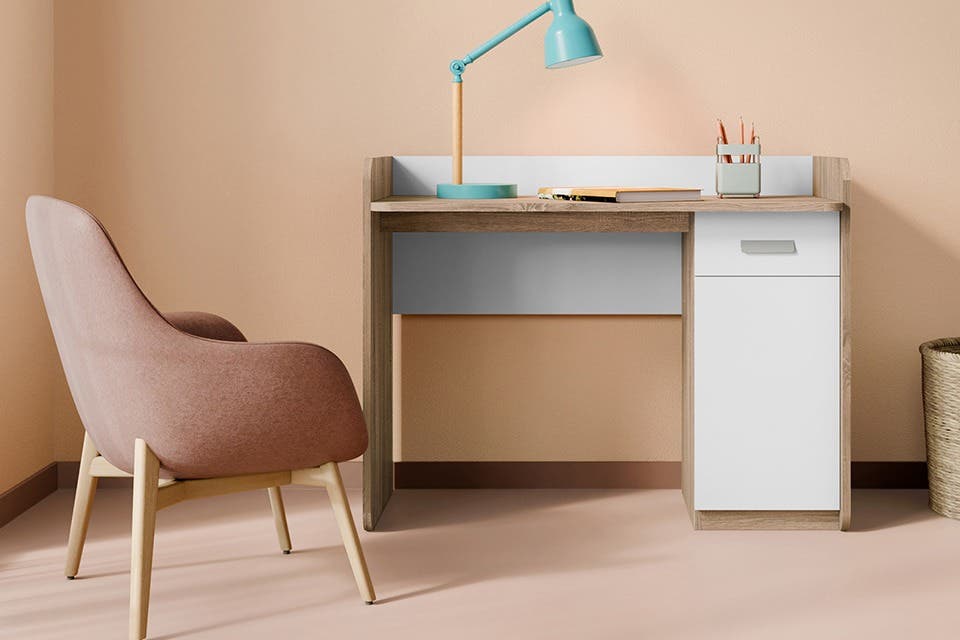 Kids’ study desk with a comfy chair, shelves and desk lamp in a bright bedroom.