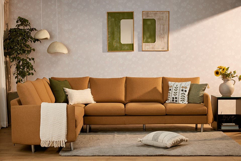 Fabric sofa complete with soft furnishings set in a calming living room, with natural sunlight filtering in.