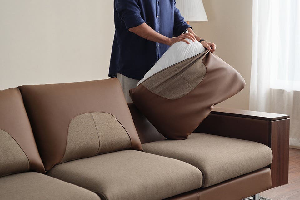 Person removing the cushion cover on a contemporary fabric sofa.