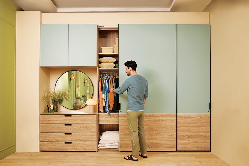 Person standing at a contemporary wardrobe with coloured panels in a stylish bedroom.