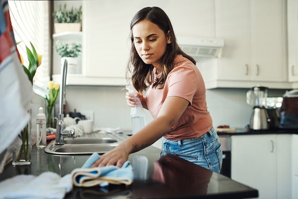 A person cleaning a kitchen countertop with a cloth.