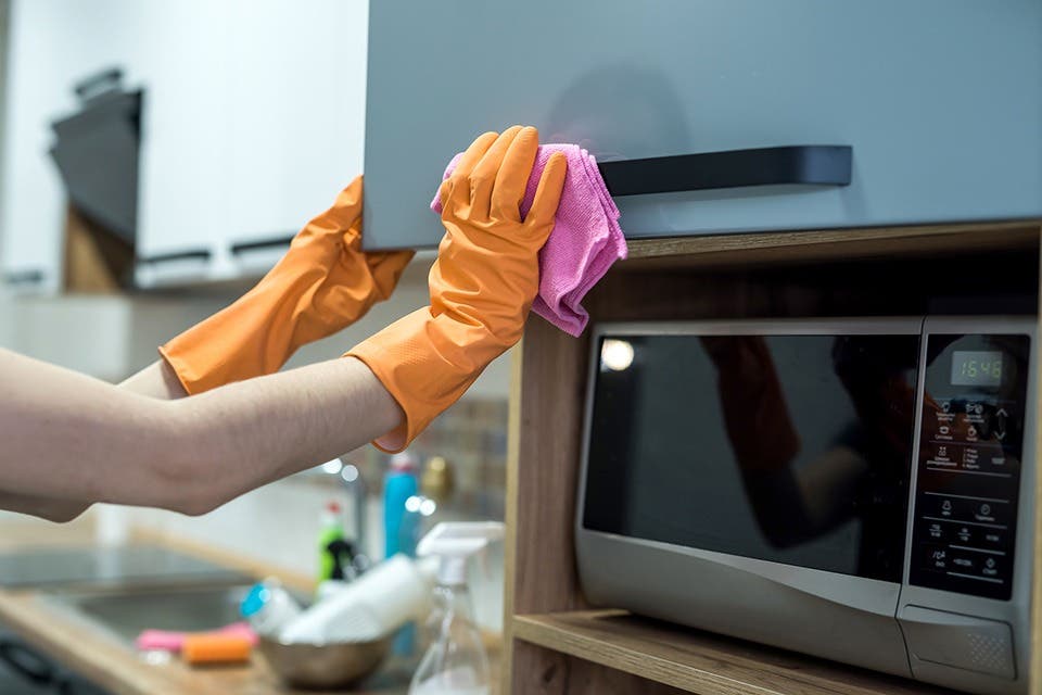 Person gently wiping a modular kitchen cabinet handle.