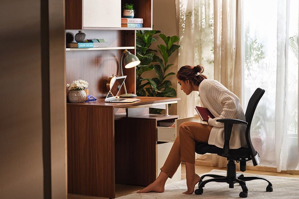 Person working at a wooden study desk with shelves in a contemporary study room.