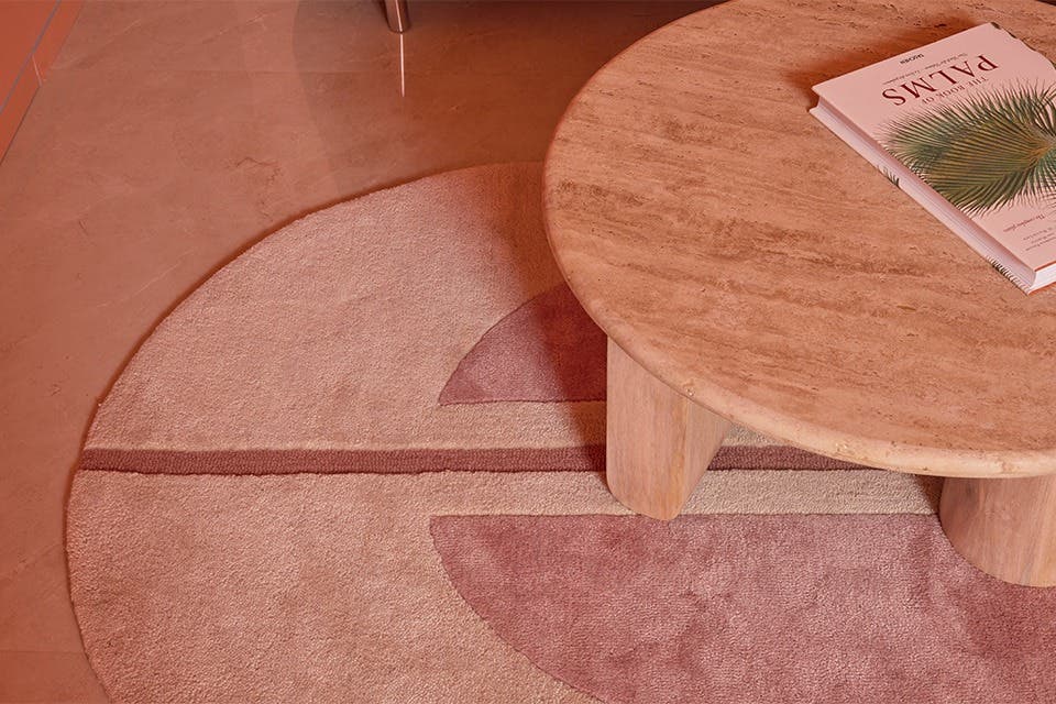 Minimalist living room styled with a textured rug and a wooden coffee table, in muted earthy shades.