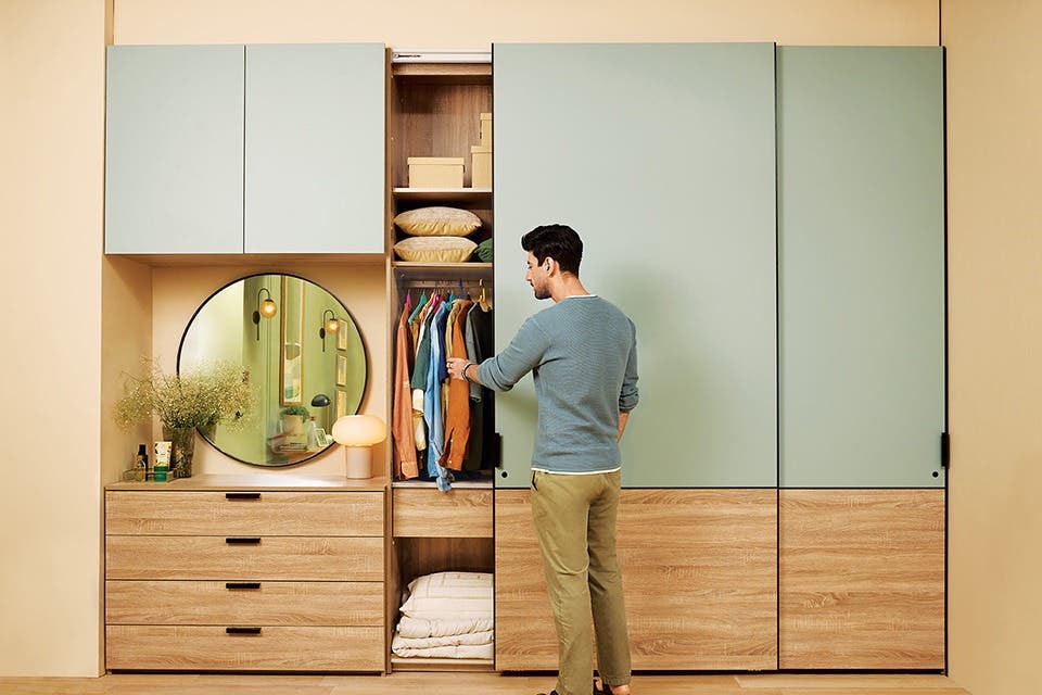 A person at a modular wardrobe with designated storage for soft furnishings, seasonals, and regular clothes.