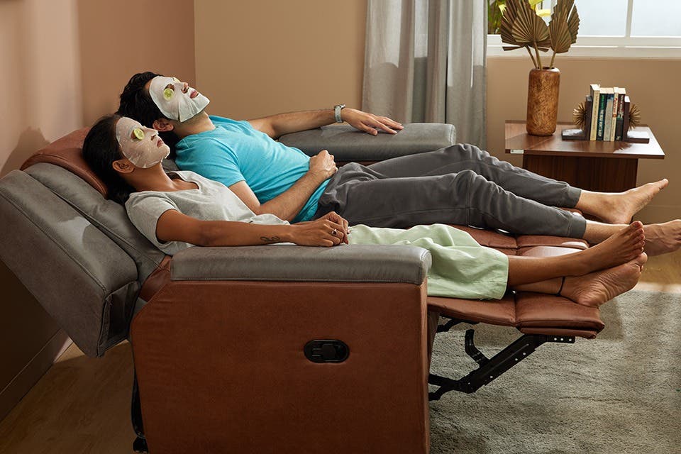  Indian couple relaxing on a contemporary Interio power recliner in a modern home.