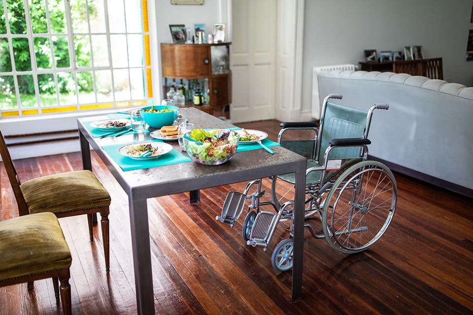 A dining setup with standard chairs on one end and a wheelchair at the other.