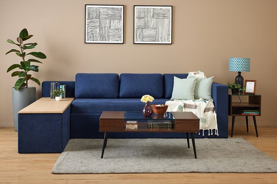 A deep blue sofa with soft furnishings in a modern Indian home.