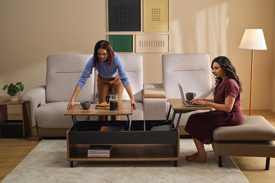 Two people using an expandable coffee table with a modern Interio sofa in the background.