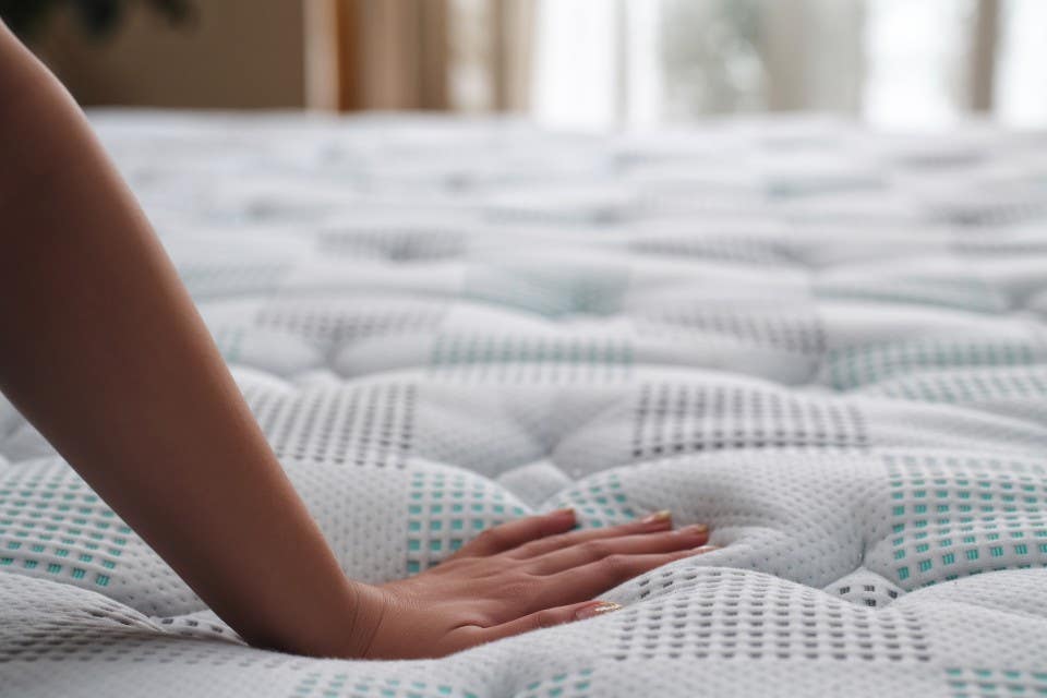 Close-up of hands pressing into a mattress to check its firmness. 